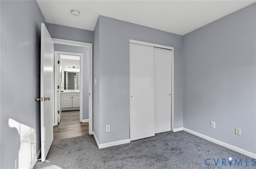 Room featuring wall-to-wall carpeting, neutral interior paint, and a sliding-door closet