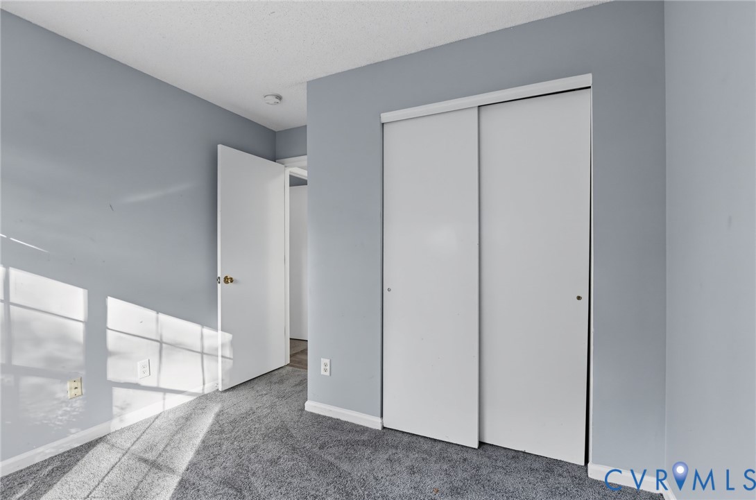 Room featuring grey carpeting, neutral wall paint, and a sliding-door closet