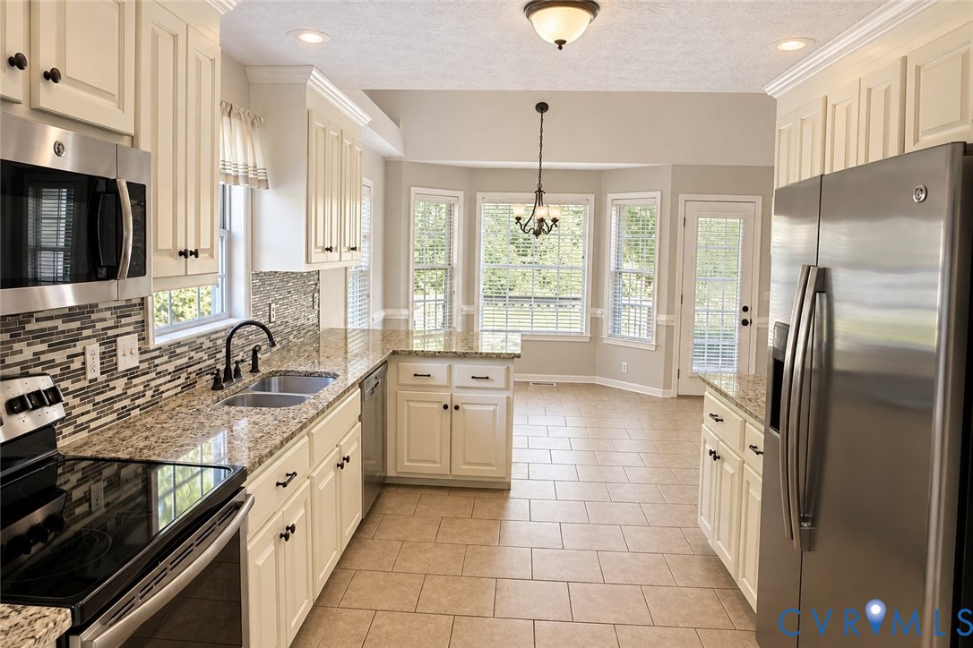 Kitchen featuring custom cabinetry, stone-finish countertops, decorative tile backsplash, stainless steel appliances, and tile flooring Kitchen featuring custom cabinetry, stone-finish countertops, decorative tile backsplash, stainless steel appliances, and tile flooring