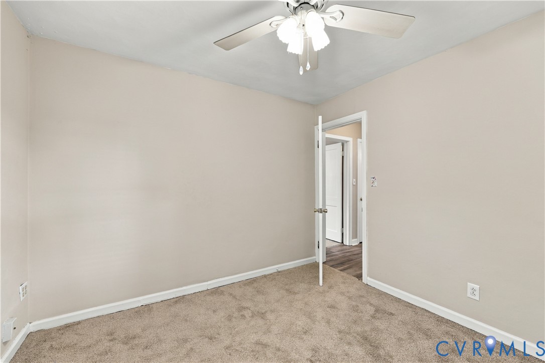Room featuring neutral wall tones, carpeted flooring, and a ceiling-mounted light fixture with a three-blade fan
