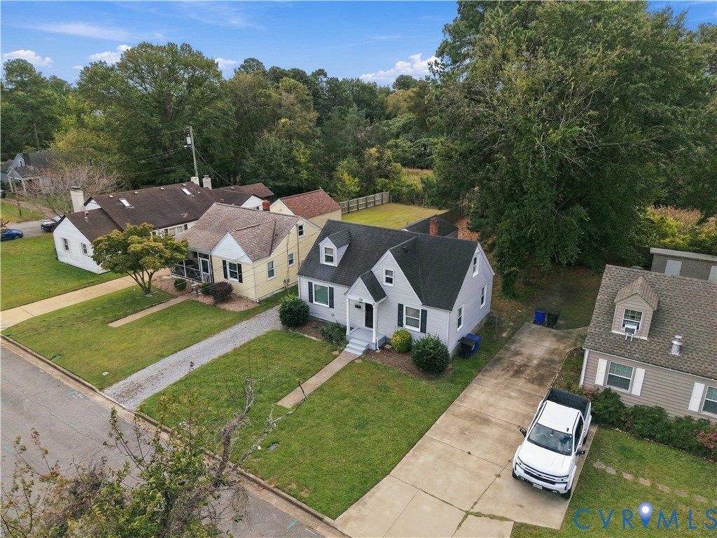 Cape Cod exterior featuring a gabled roofline, dormer windows, concrete driveway, and front lawn
