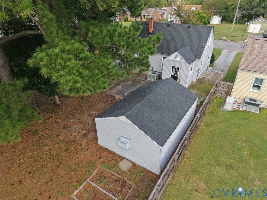 Exterior features include a detached garage with dark shingle roofing, a partial wood privacy fence, and a designated garden plot area