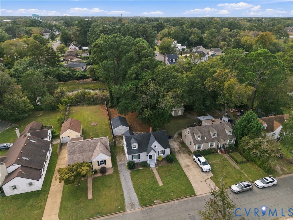 Aerial view featuring a two-story residence with a gabled roof, detached garage, and mature tree canopy on a lot with grass landscaping