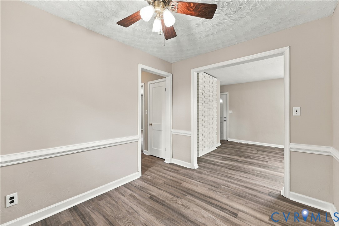 Interior featuring wood-finish flooring, white chair rail molding, a textured ceiling, and a ceiling-mounted light fixture with a fan