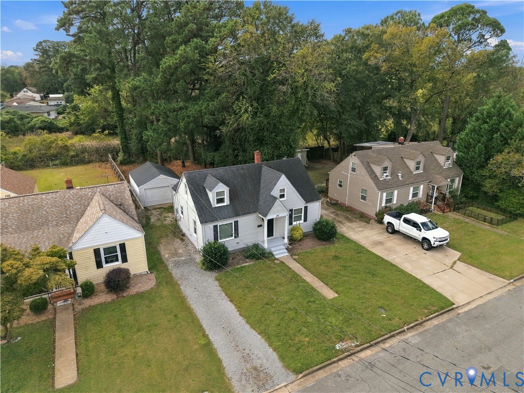 Cape Cod exterior featuring a gabled roofline, dormer windows, a covered front entryway, and a detached single-car garage