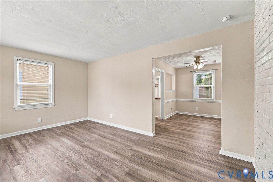Living space featuring wood-finish flooring, painted brick wall, recessed wall opening, and multi-pane windows