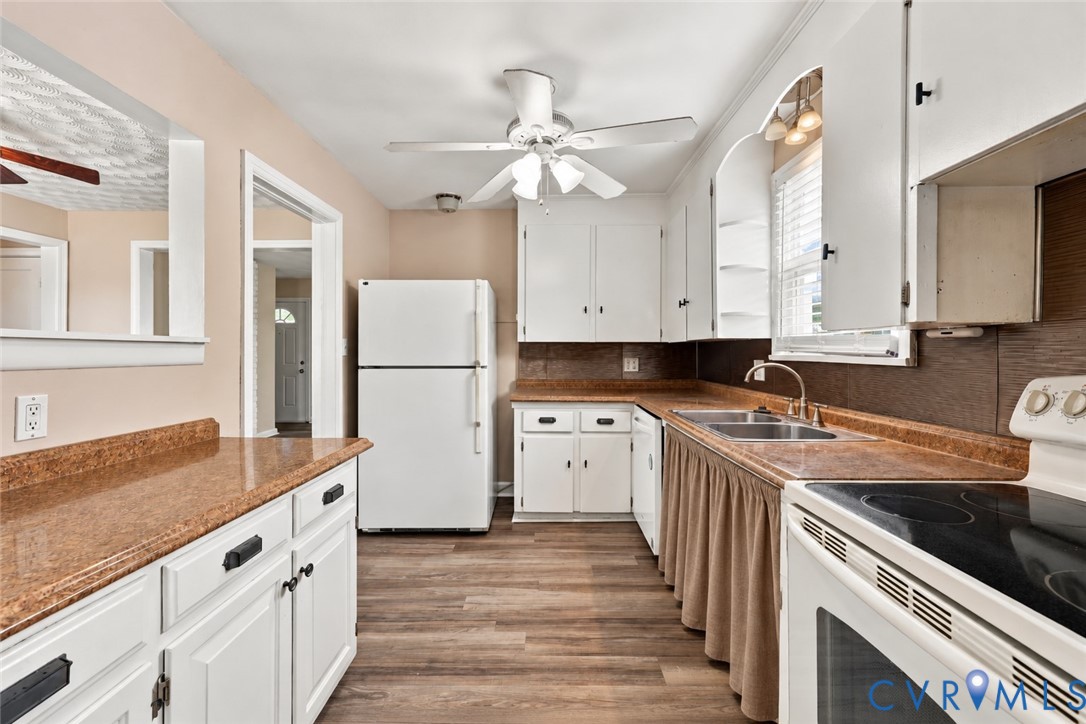 Kitchen featuring wood-finish flooring, white cabinetry, dark countertops, a double-basin sink, and a ceiling fan