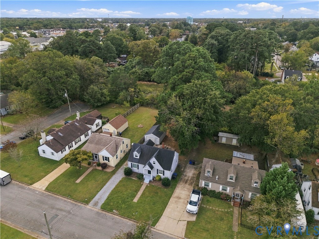 Aerial perspective of a residential lot featuring a detached storage structure, concrete driveway, and established tree canopy