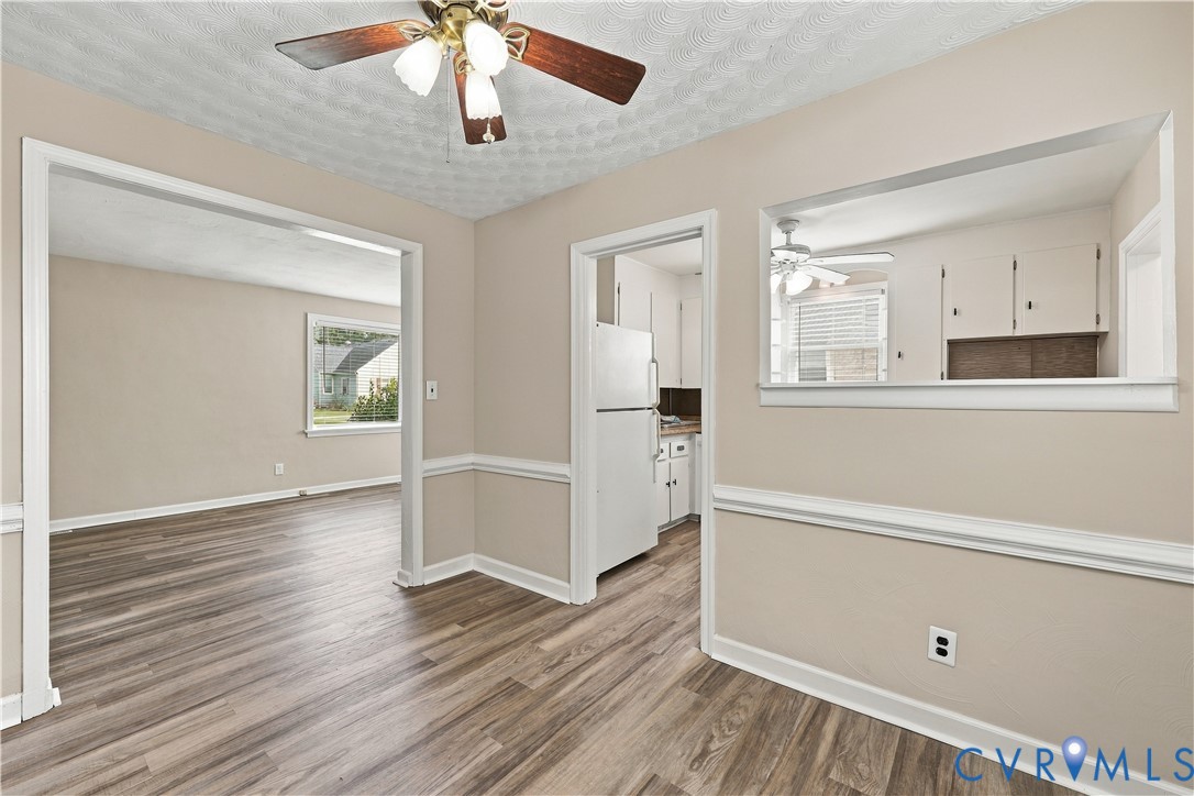 Interior space featuring wood-finish flooring, chair rail molding, and a ceiling-mounted light fixture with integrated fan