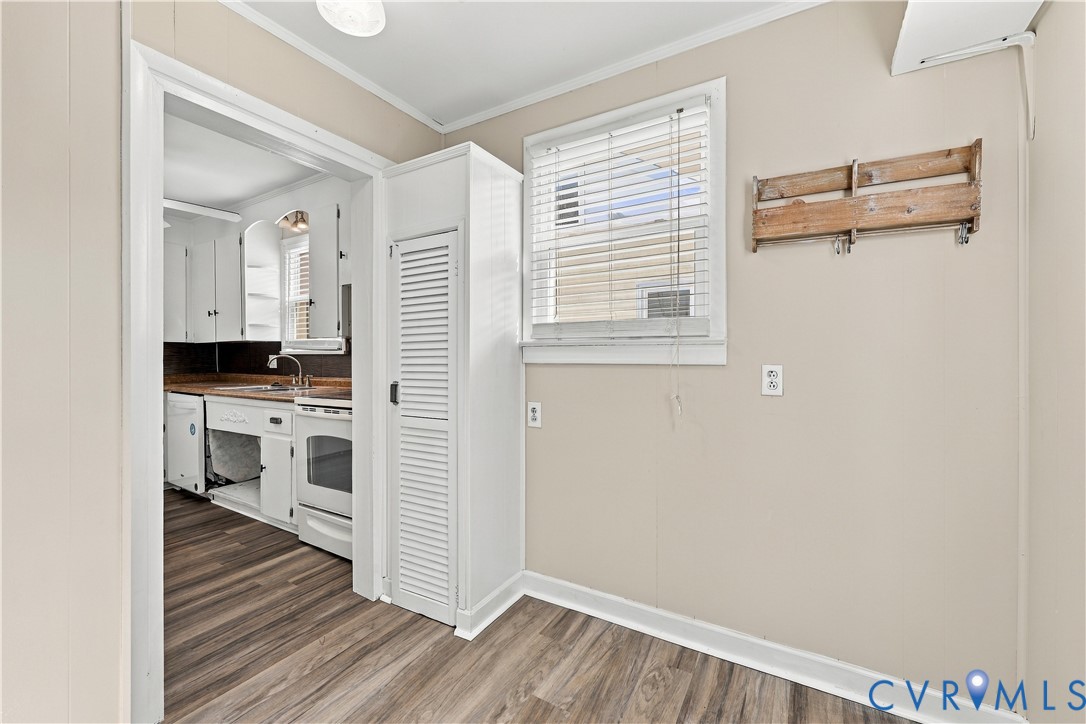 Wood-finish flooring, white louvered pantry cabinet, and double-hung window with blinds