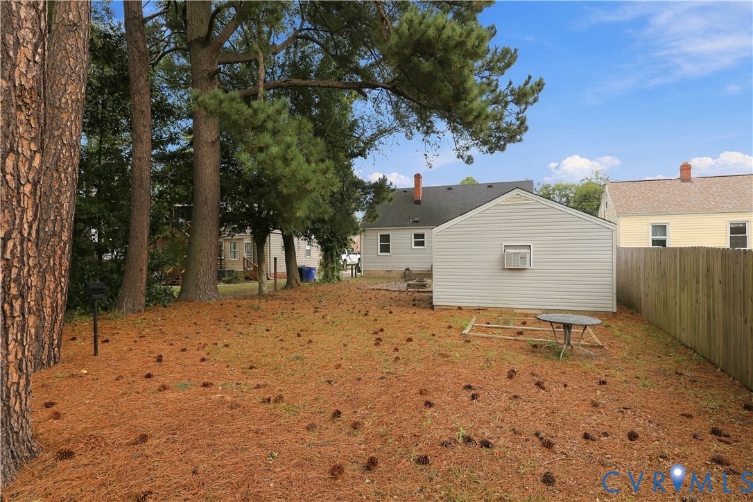 Spacious backyard featuring mature trees, detached garage, and wood-paneled privacy fencing