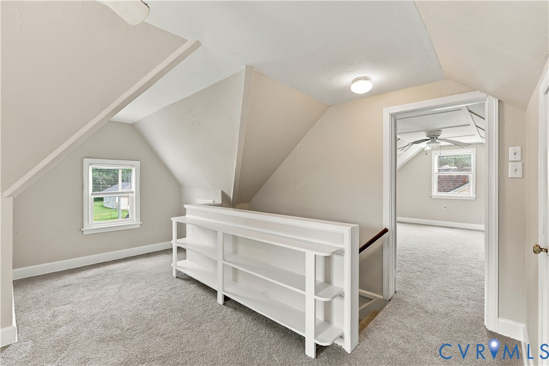 Vaulted ceilings with architectural roof lines, built-in shelving, neutral wall tones, and double-hung windows