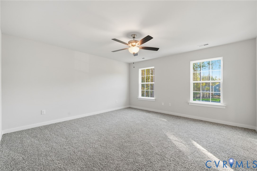 Neutral interior featuring wall-to-wall carpeting, dual windows, and a ceiling-mounted light fixture with fan blades