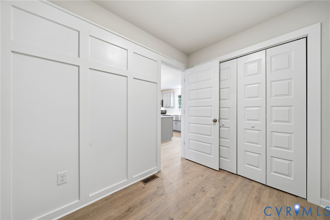 Wall with custom board-and-batten millwork, wood-finish flooring, and multi-panel interior doors