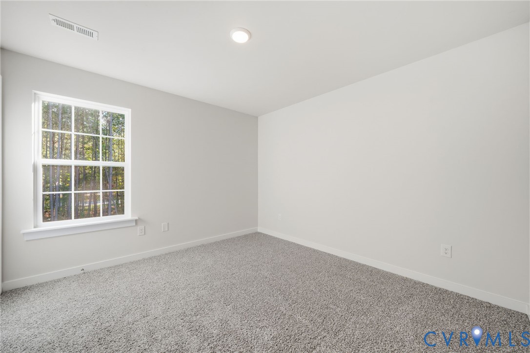 Neutral-toned interior featuring wall-to-wall carpeting, a multi-pane window, and a flush-mount ceiling light fixture