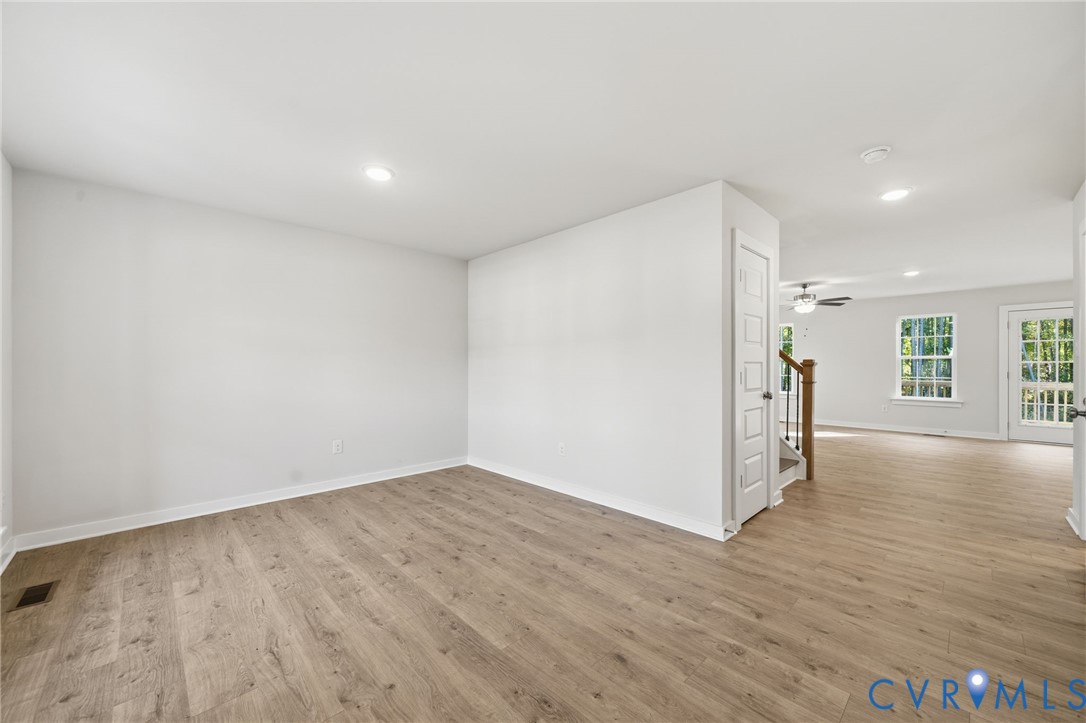 Neutral-toned interior space featuring wood-finish flooring, recessed lighting, multi-panel interior doors, and grid-pattern window panes