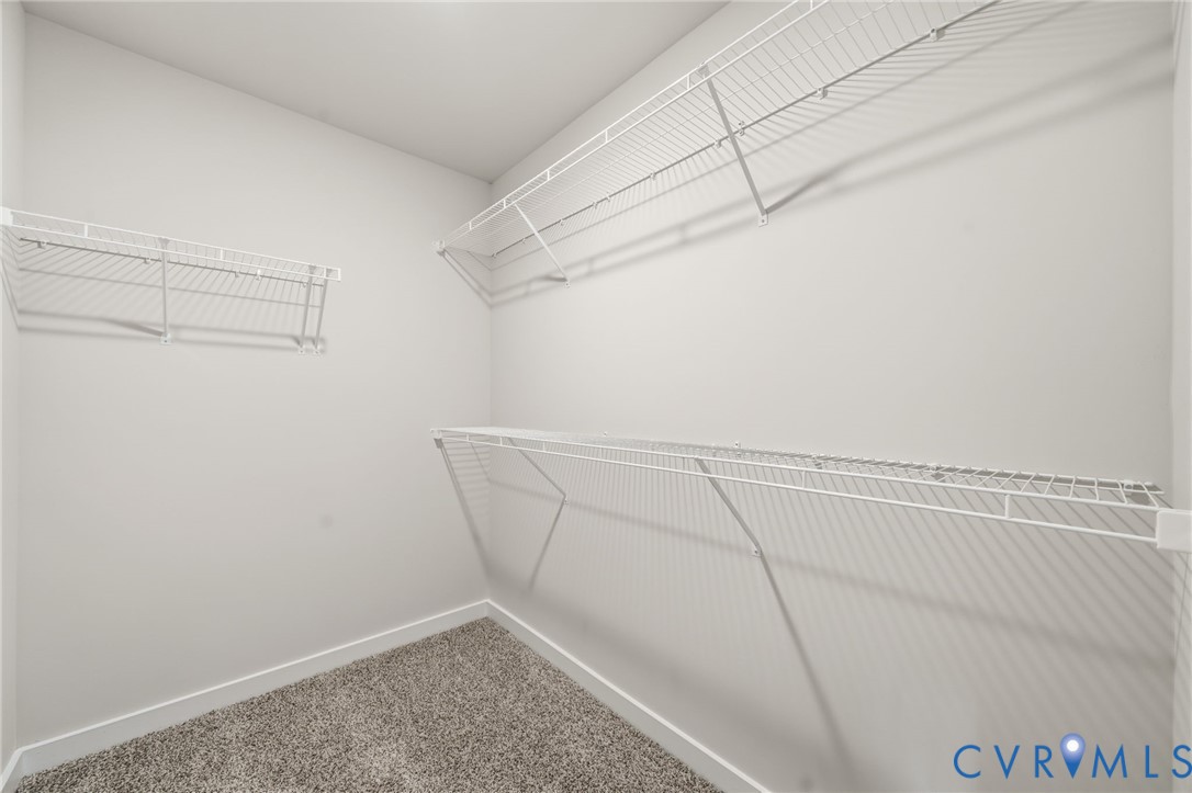 Storage space featuring wall-mounted wire shelving and carpeting