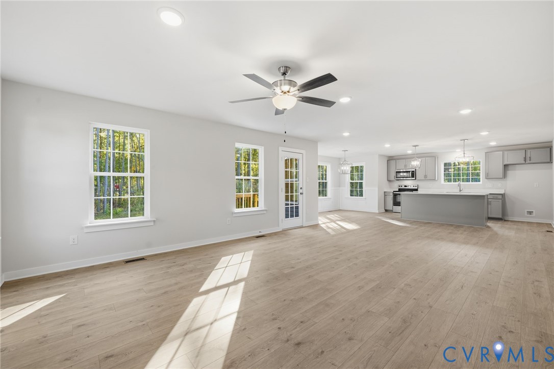 Open-concept interior featuring wood-finish flooring, recessed lighting, a ceiling fan, and a kitchen equipped with a central island and cabinetry