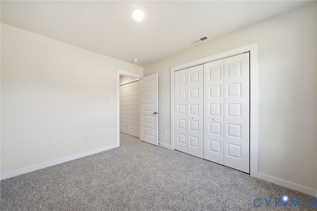 Neutral-toned carpeted flooring, white interior walls, and bi-fold closet doors with raised-panel detailing