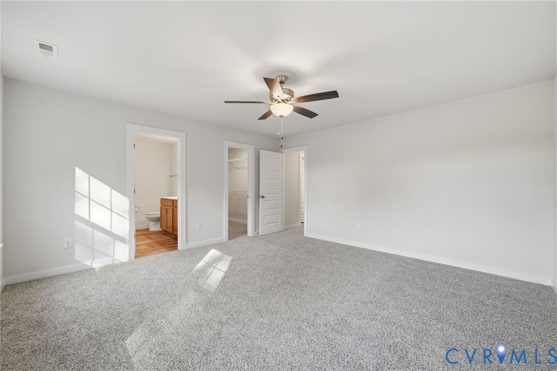 Neutral-toned carpeted room featuring a ceiling fan with integrated lighting and multi-panel interior doors