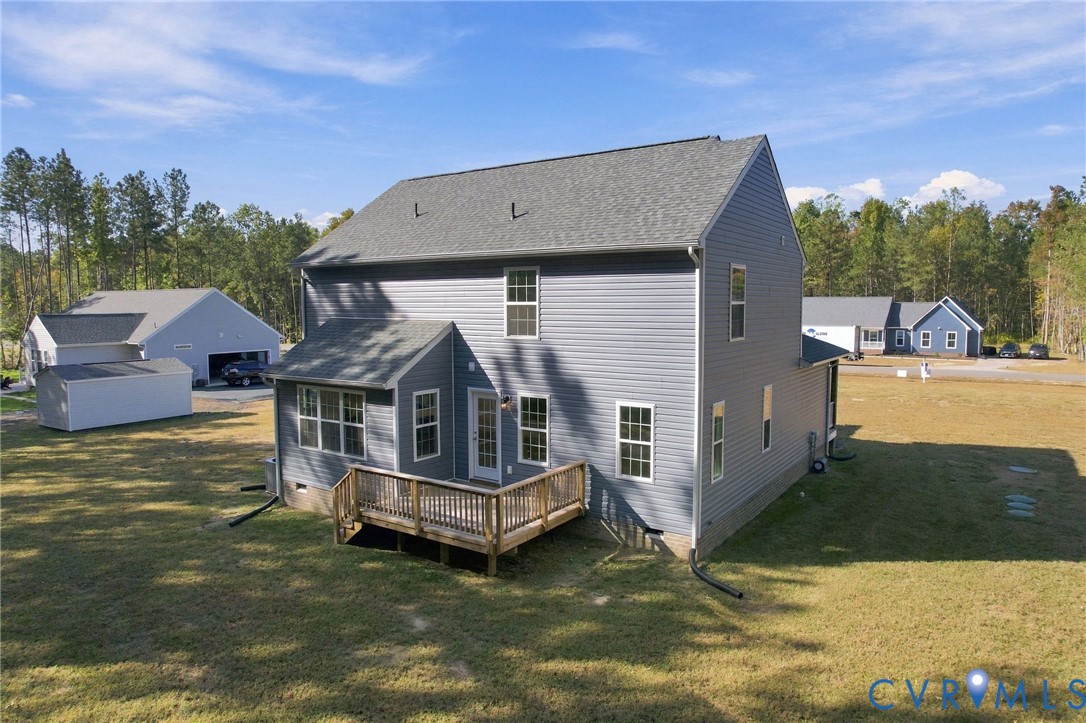 Two-story residence featuring gray vinyl siding, an asphalt shingle roof, a detached garage, and a wood deck