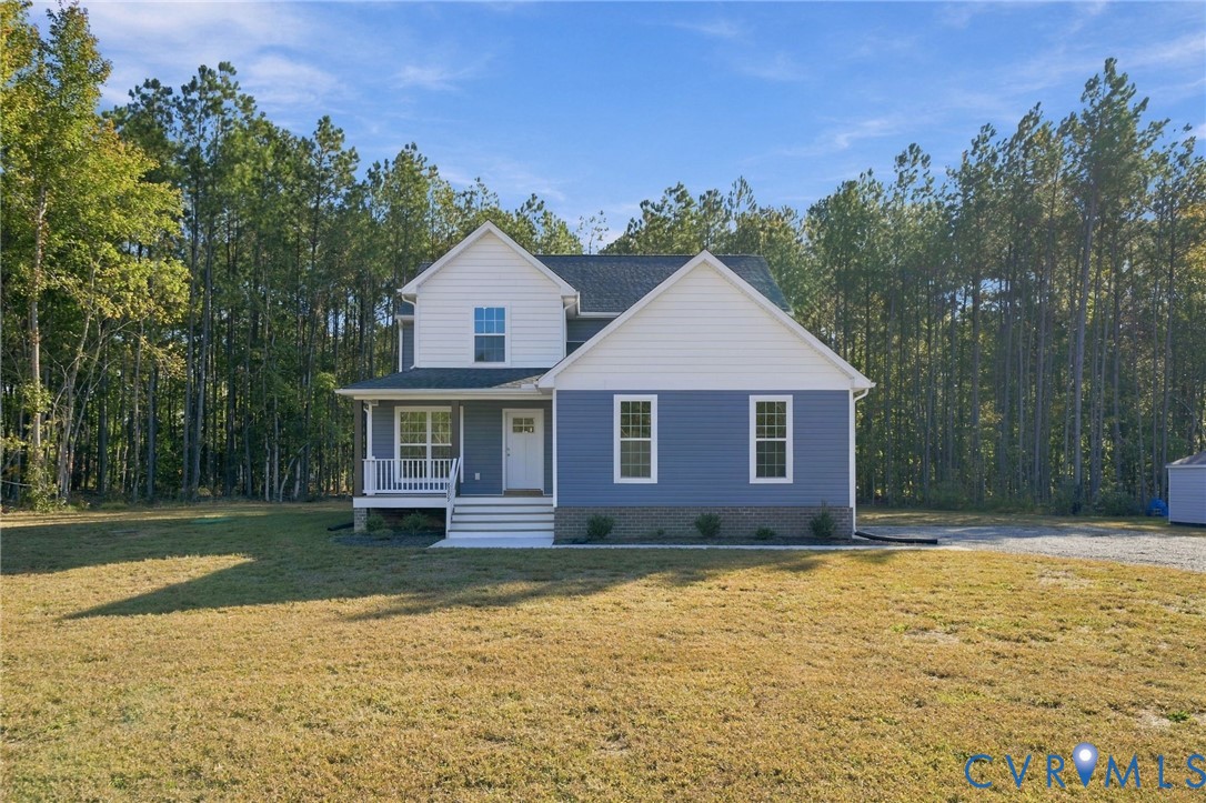 Two-story residence featuring blue and white horizontal siding, a covered front porch, brick foundation detailing, and a shingled roof