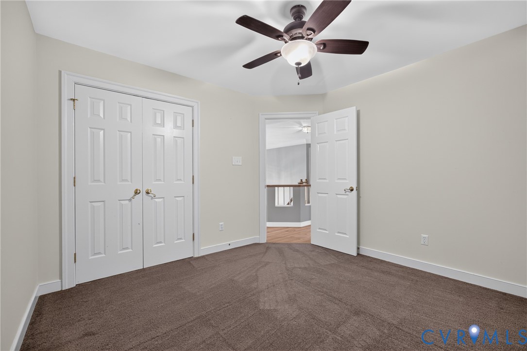 Neutral-toned walls, ceiling fan with integrated lighting, wall-to-wall carpeting, and double-panel doors