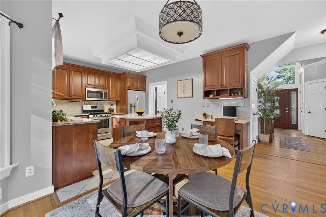 Kitchen featuring wood cabinetry, stone countertops, stainless steel appliances, a built-in workstation, and a tray ceiling with recessed lighting