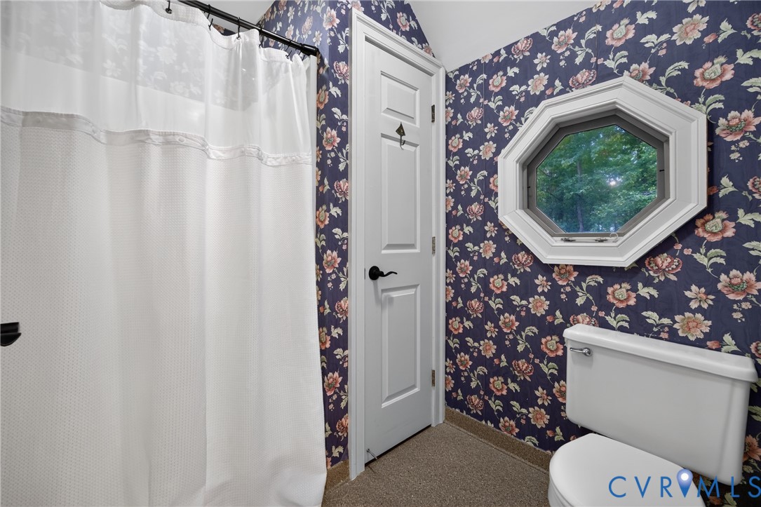 Octagonal window with white trim, floral wallpaper, and a four-panel interior door with matte black hardware