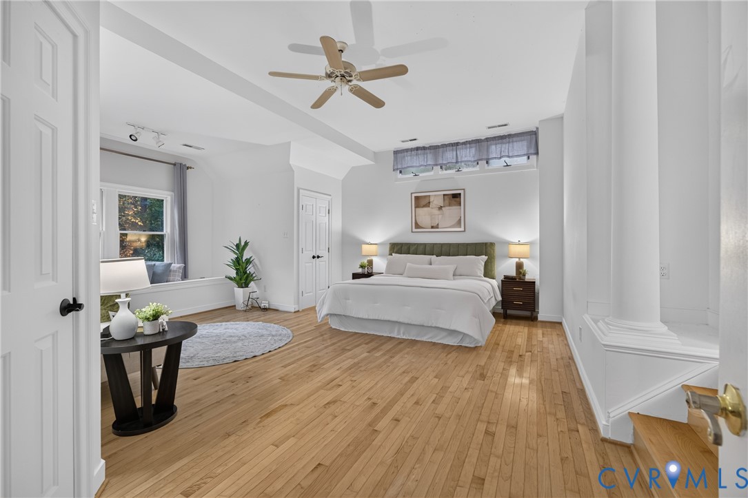 Spacious room featuring wood-finish flooring, a ceiling fan, a recessed window seat, and transoms above the window