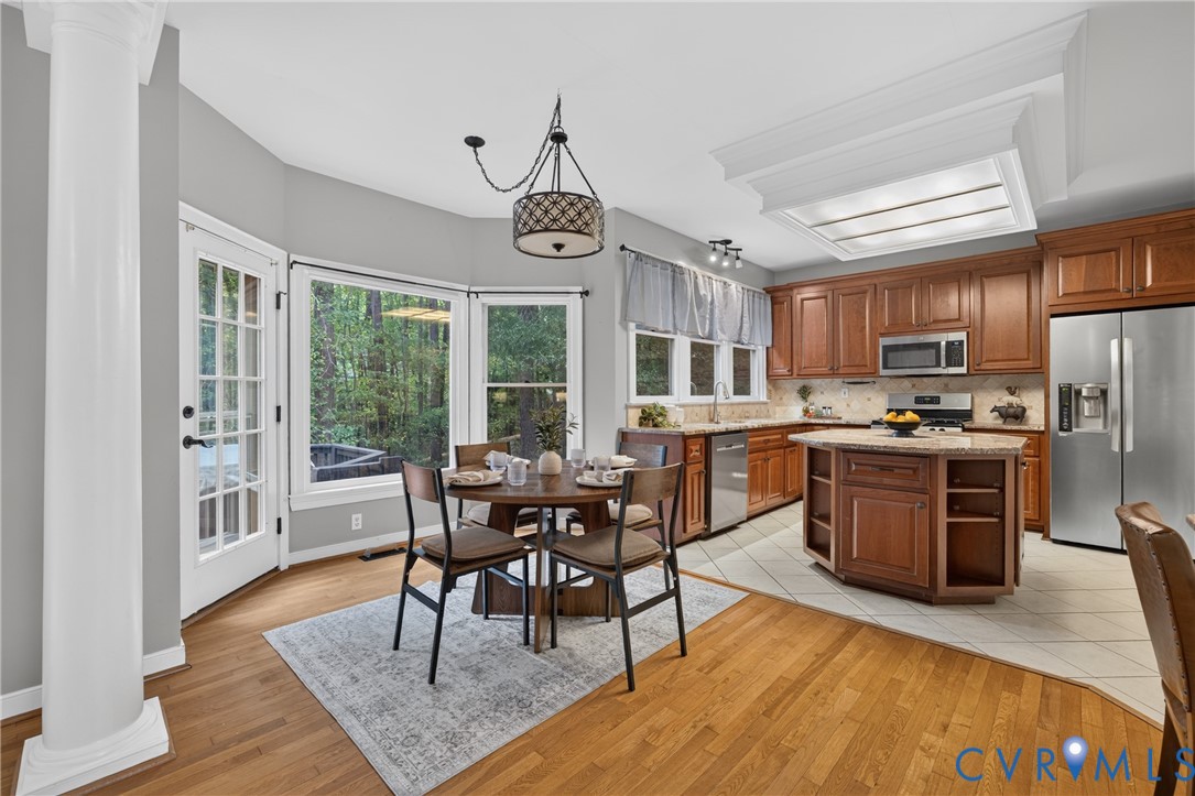 Kitchen featuring wood cabinetry, an island with stone countertops, stainless steel appliances, recessed ceiling lighting, and wood-finish flooring