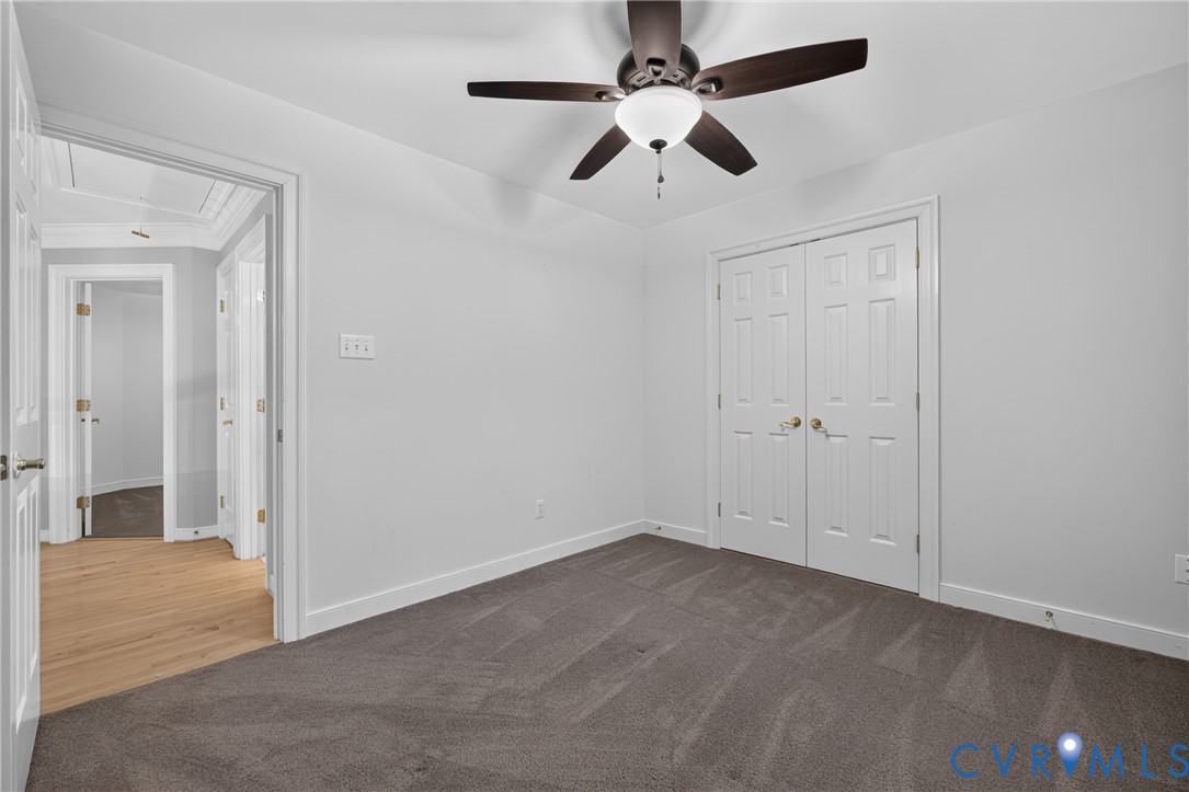 Interior room featuring neutral carpeting, a ceiling fan with integrated lighting, and a double-door closet
