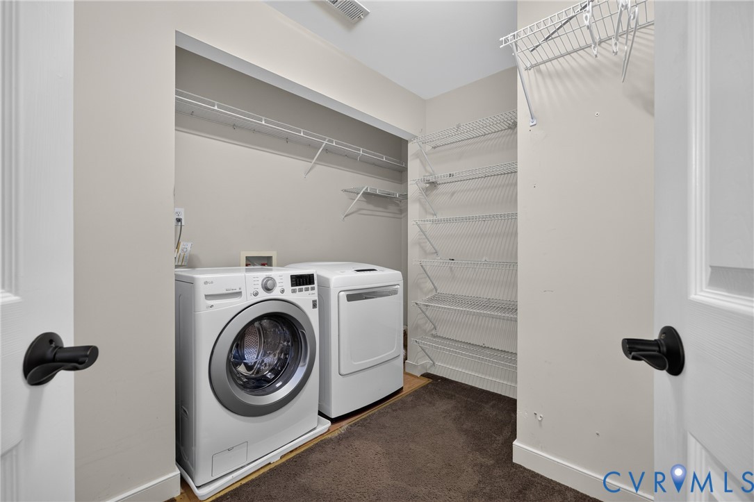 Laundry area featuring wire shelving units, carpeted flooring, and doors with matte black hardware