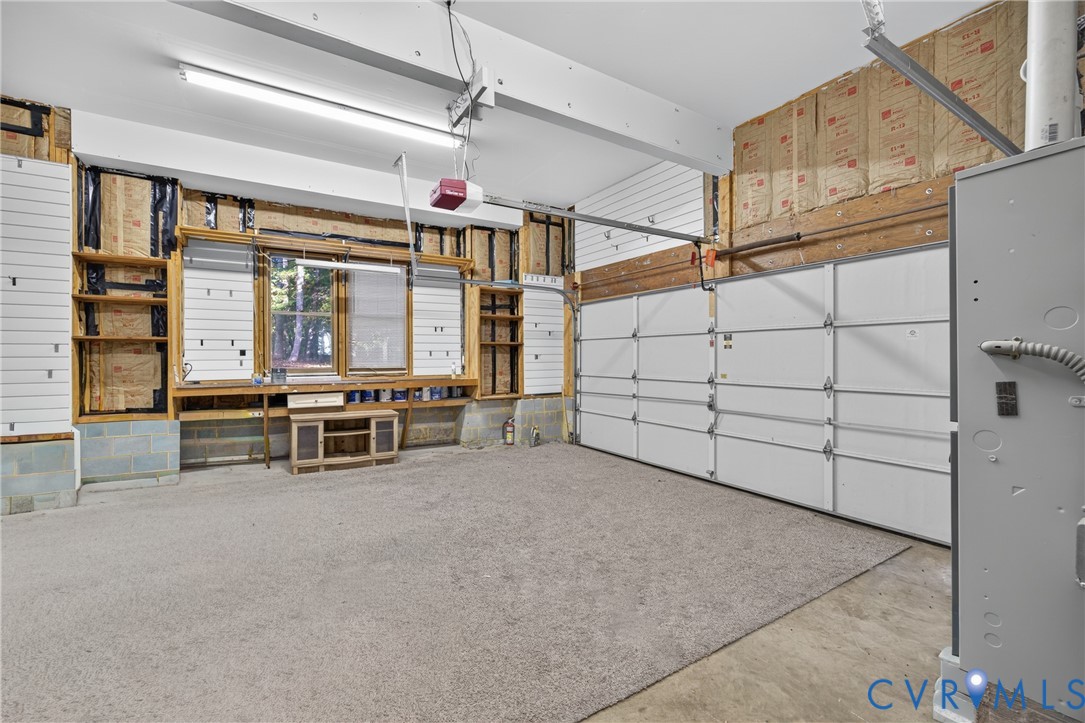 Garage space featuring a paneled sectional door, concrete flooring, built-in wooden workbench, and fluorescent overhead lighting