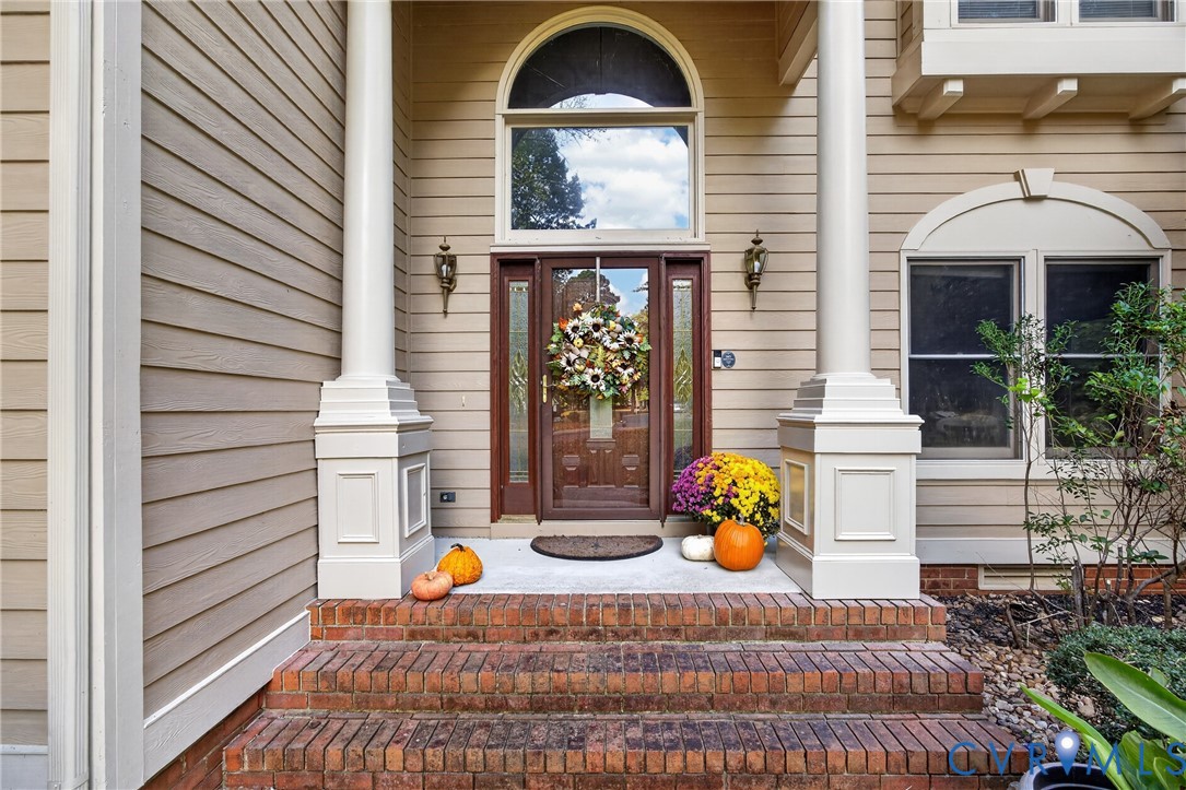 Front entryway featuring a brick staircase, dual structural columns, arched transom window, and paneled wood door with glass sidelights Front entryway featuring a brick staircase, dual structural columns, arched transom window, and paneled wood door with glass sidelights