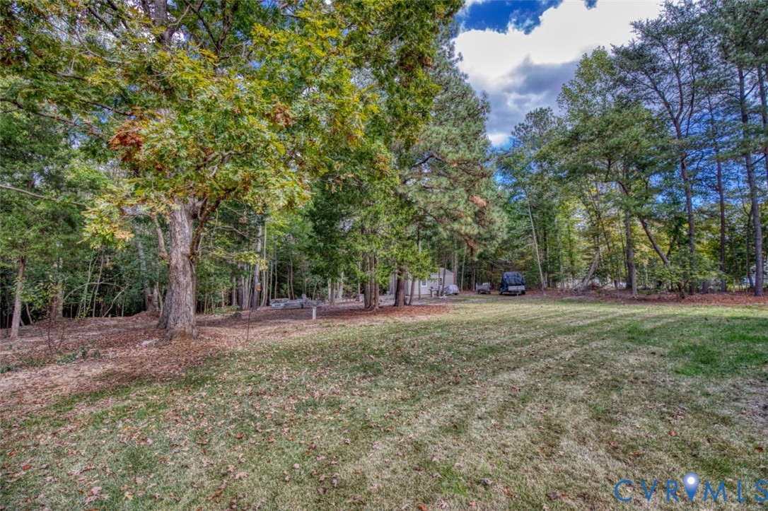 Expansive backyard featuring an open grass lawn, mature trees, and a heavily wooded perimeter Expansive backyard featuring an open grass lawn, mature trees, and a heavily wooded perimeter