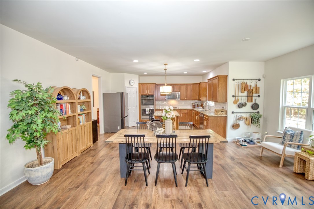 Kitchen featuring wood-finish cabinetry, built-in double wall ovens, recessed lighting, and expansive wood-finish flooring