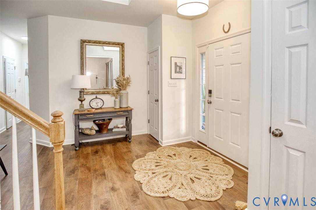 Foyer featuring wood-finish flooring, a white paneled front door with sidelight, and a pendant light fixture