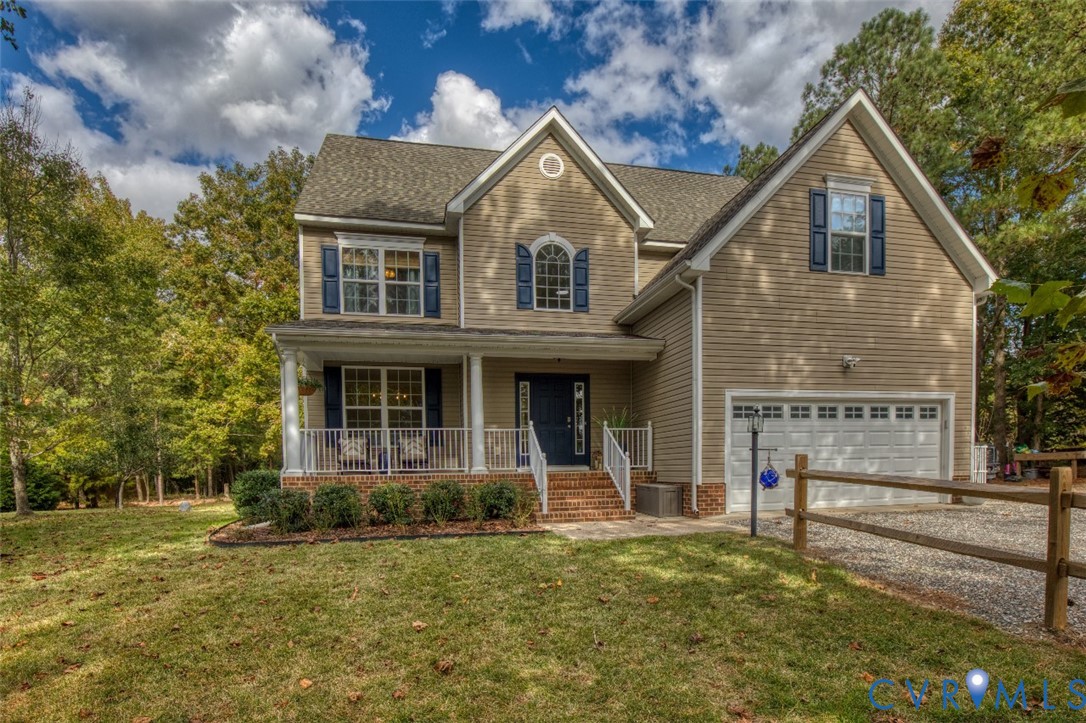 Two-story residence featuring horizontal siding, a covered front porch with white railing, brick-accented stairs, a multi-gabled roofline, and a multi-car garage