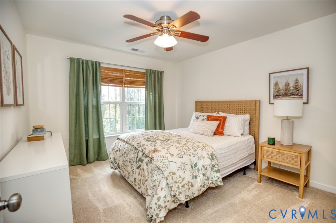 Neutral-toned wall-to-wall carpeting, multi-pane window with wood-slat blinds, and a central ceiling fan with integrated lighting
