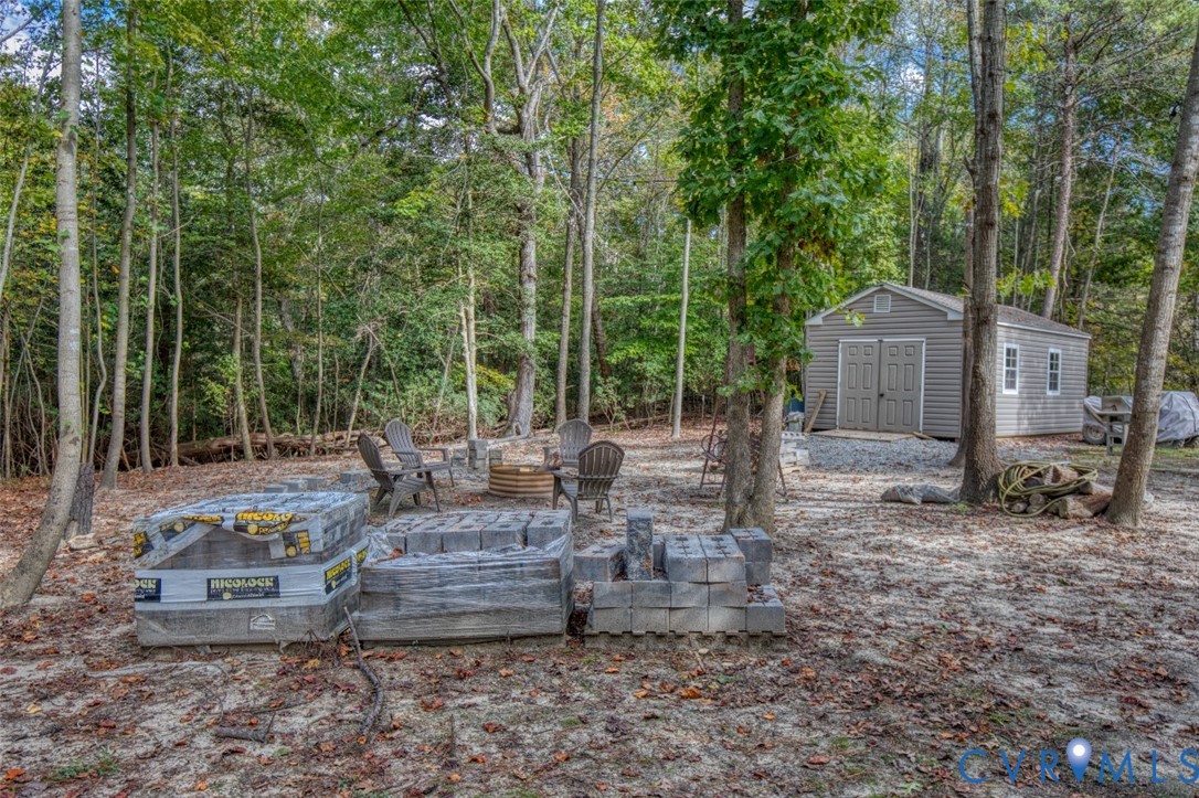 Wooded lot featuring a detached storage building with vinyl siding and a gravel foundation Wooded lot featuring a detached storage building with vinyl siding and a gravel foundation