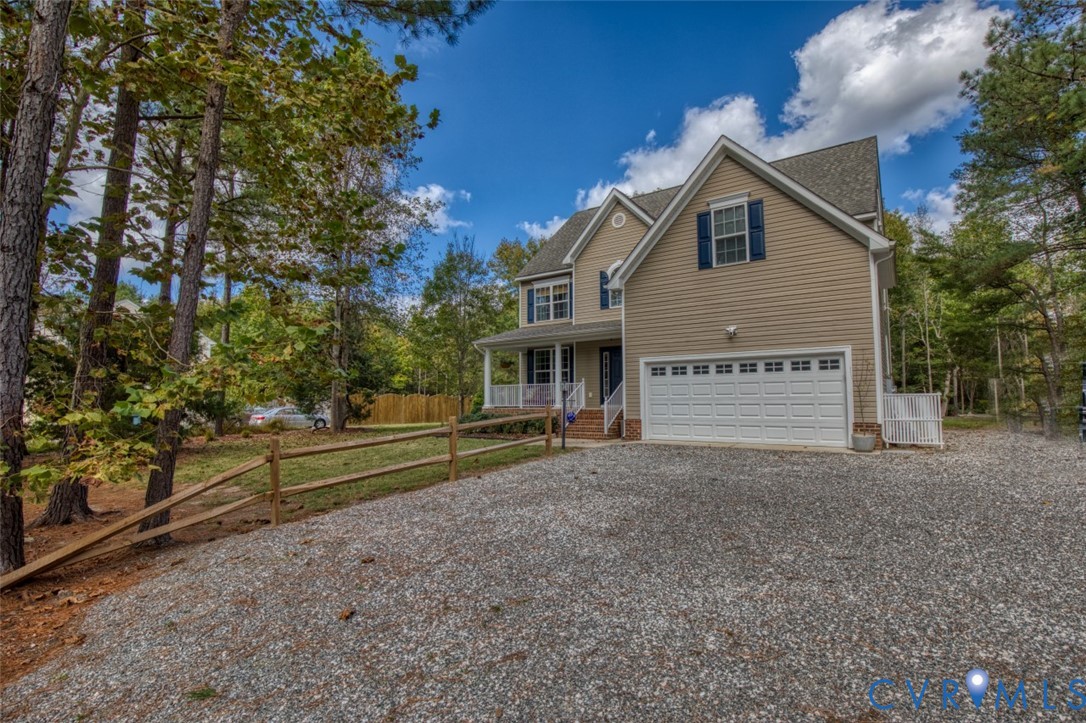 Two-story residential exterior featuring neutral vinyl siding, a two-car garage, shuttered windows, and a covered front porch with a white railing Two-story residential exterior featuring neutral vinyl siding, a two-car garage, shuttered windows, and a covered front porch with a white railing