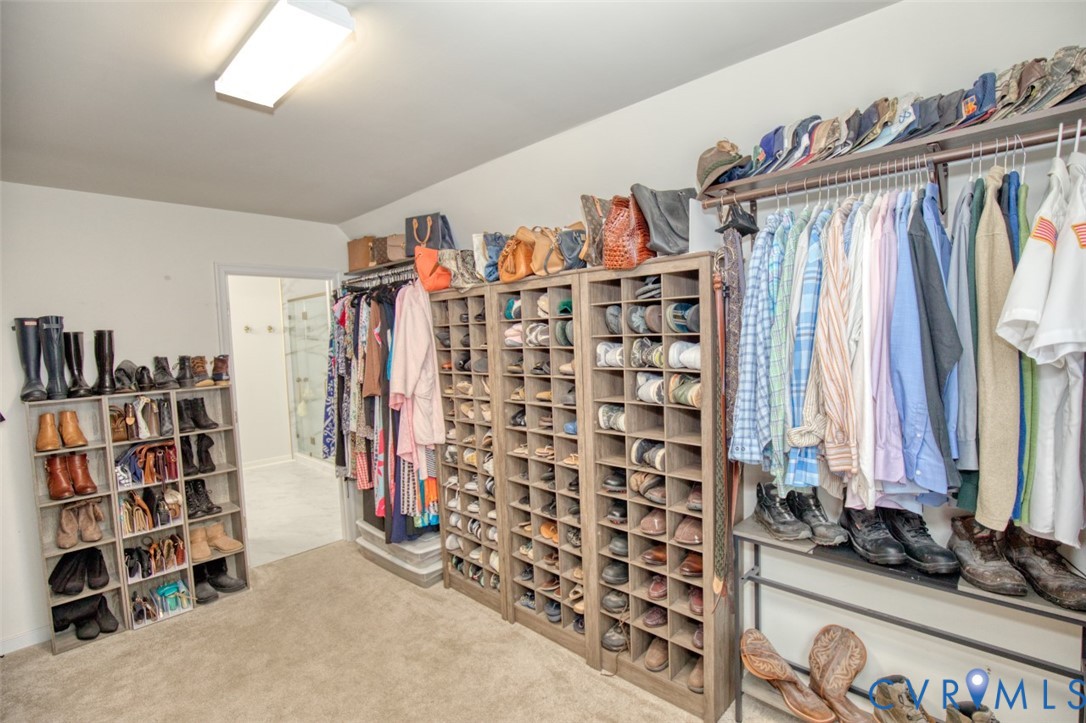 Walk-in closet featuring extensive built-in shelving, modular cubbies, wall-to-wall carpeting, and linear hanging rods