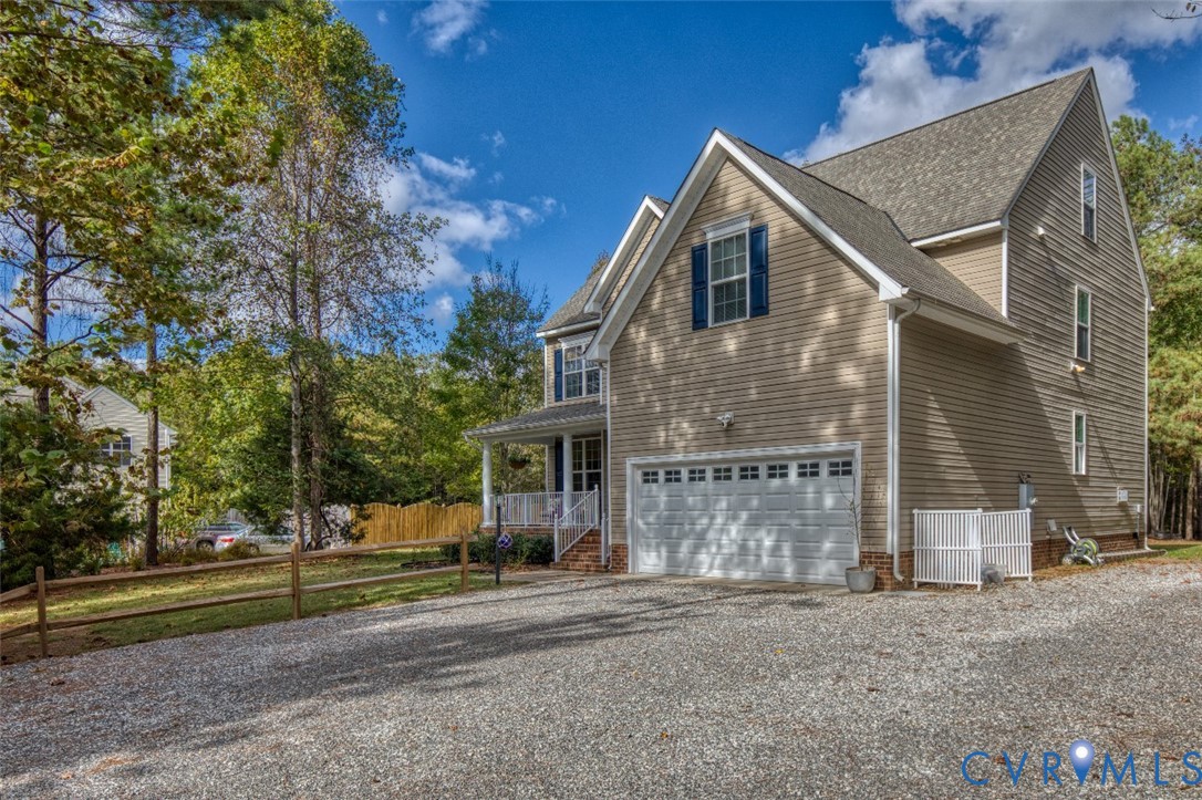 Two-story residence featuring horizontal siding, a gabled roofline, an attached two-car garage, and a covered front porch with white railing