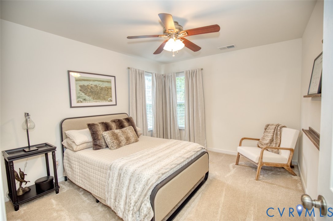 Neutral-toned carpeting, ceiling fan with integrated light fixture, and dual-window wall