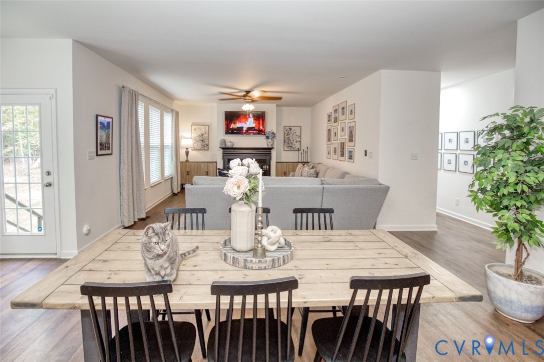 Open-concept space featuring wood-finish flooring, a fireplace with a dark mantle, built-in cabinetry, and a glass-paneled exterior door
