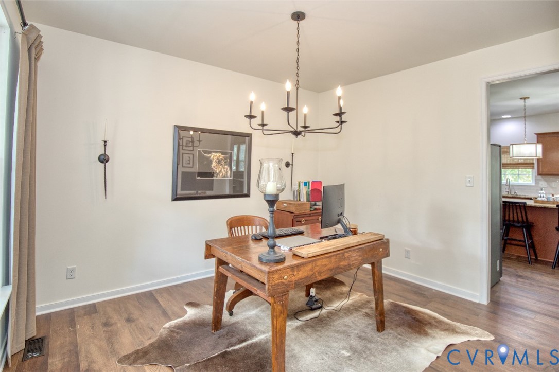 Room featuring wood-finish flooring, a six-arm metal chandelier, and a wall-mounted metal sconce