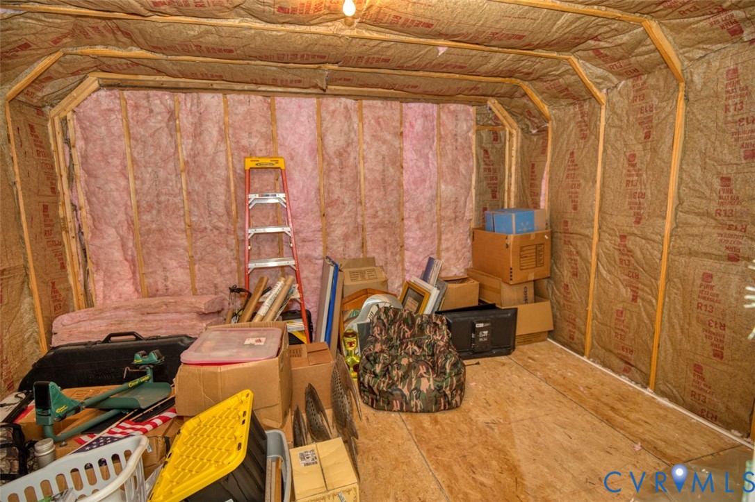 Unfinished interior space featuring exposed wood stud framing, fiberglass batt insulation, and plywood flooring