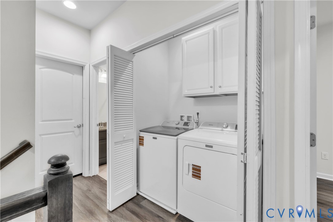 Laundry area featuring white shaker-style cabinetry, louvered bi-fold doors, and wood-finish flooring