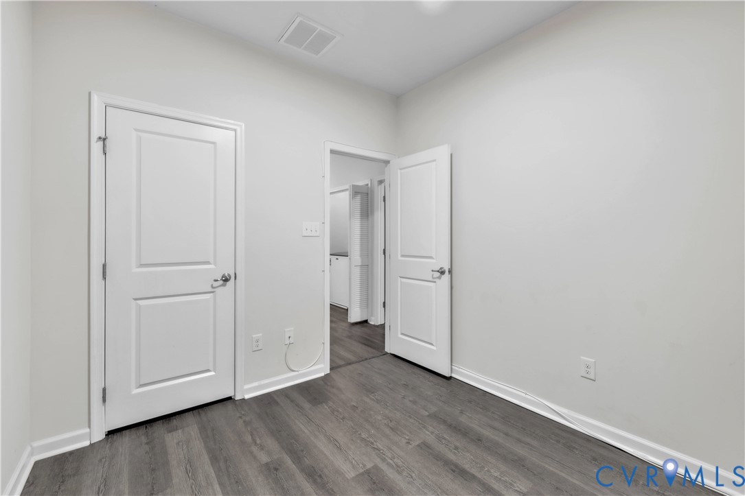 Neutral-toned interior featuring wood-finish flooring, two-panel interior doors with metallic hardware, and smooth-finish walls